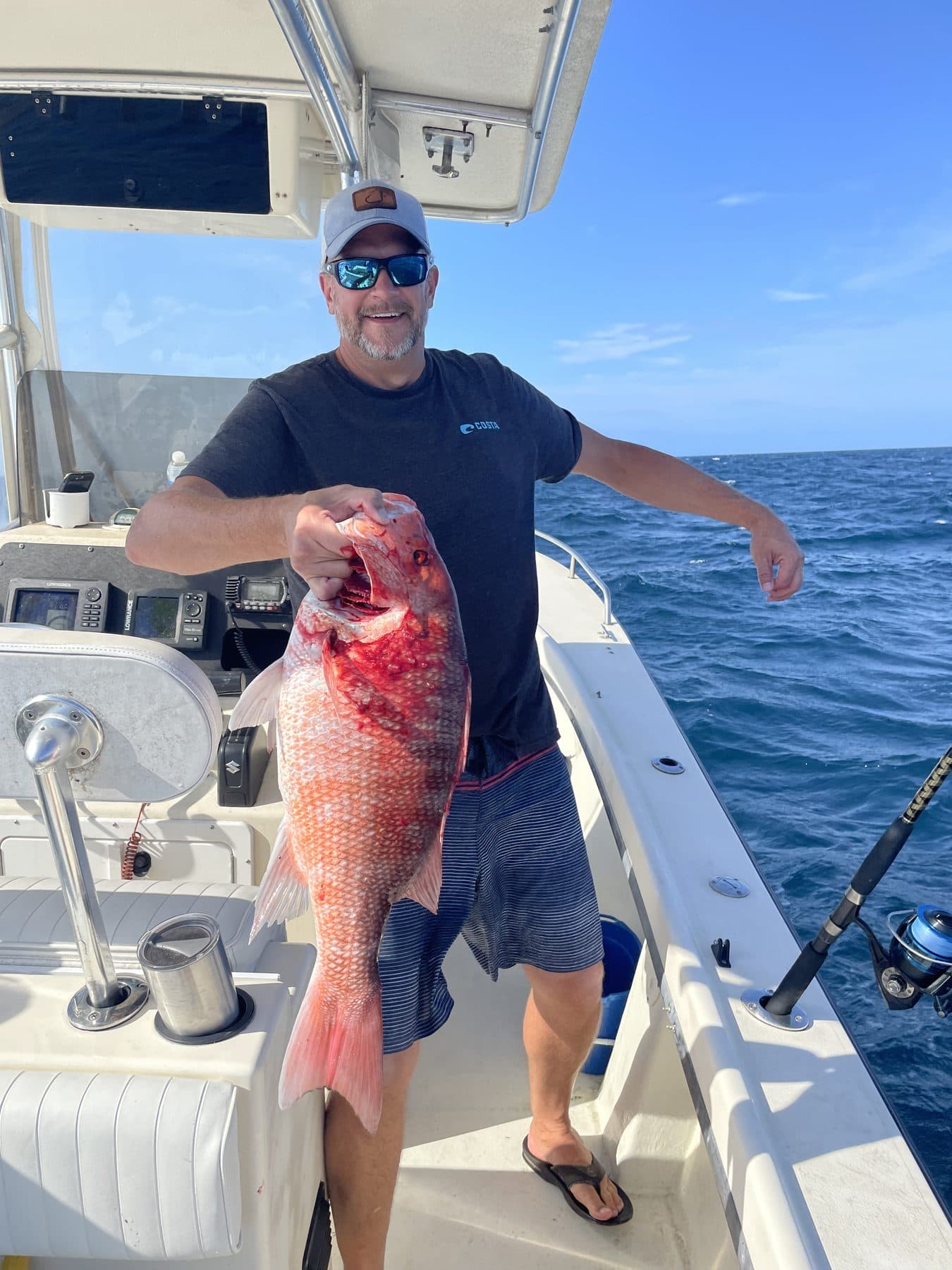 Red snapper held up on deck over blue water